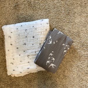 2 baby swaddle blankets. One has stars and moons and the other has swallows.